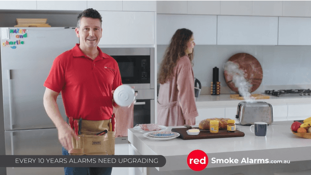 Red technician - showing home owner the smoke alarm
